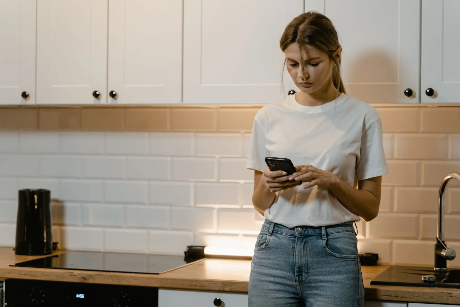 Homeowner in her kitchen searching for a local business on her phone